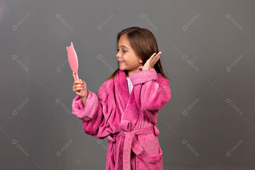Linda menina usando roupão de banho rosa sobre fundo isolado segurando espelho
