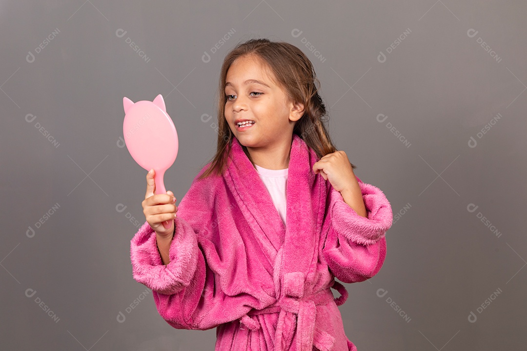 Linda menina usando roupão de banho rosa sobre fundo isolado segurando espelho