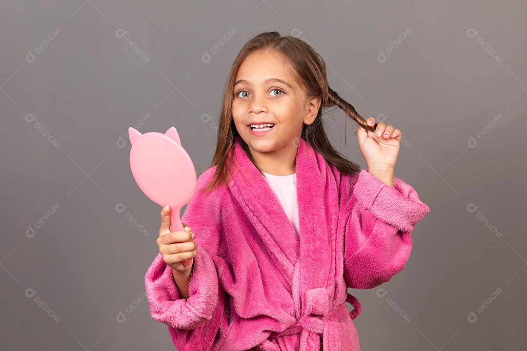 Linda menina usando roupão de banho rosa sobre fundo isolado segurando espelho