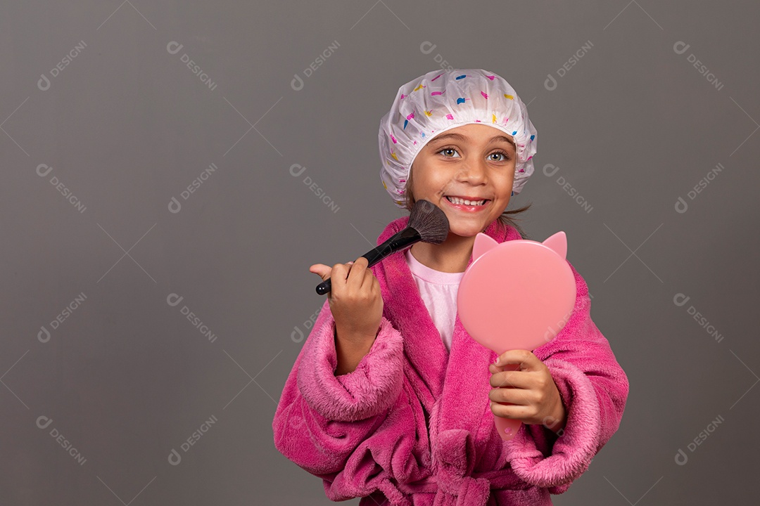 Linda menina usando roupão de banho rosa touca pincel e espelho sobre fundo isolado