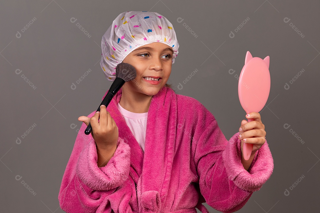 Linda menina usando roupão de banho rosa touca pincel e espelho sobre fundo isolado