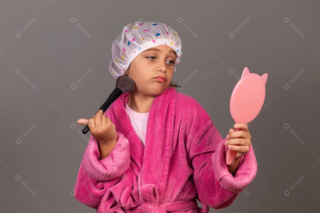 Linda menina usando roupão de banho rosa touca pincel e espelho sobre fundo isolado