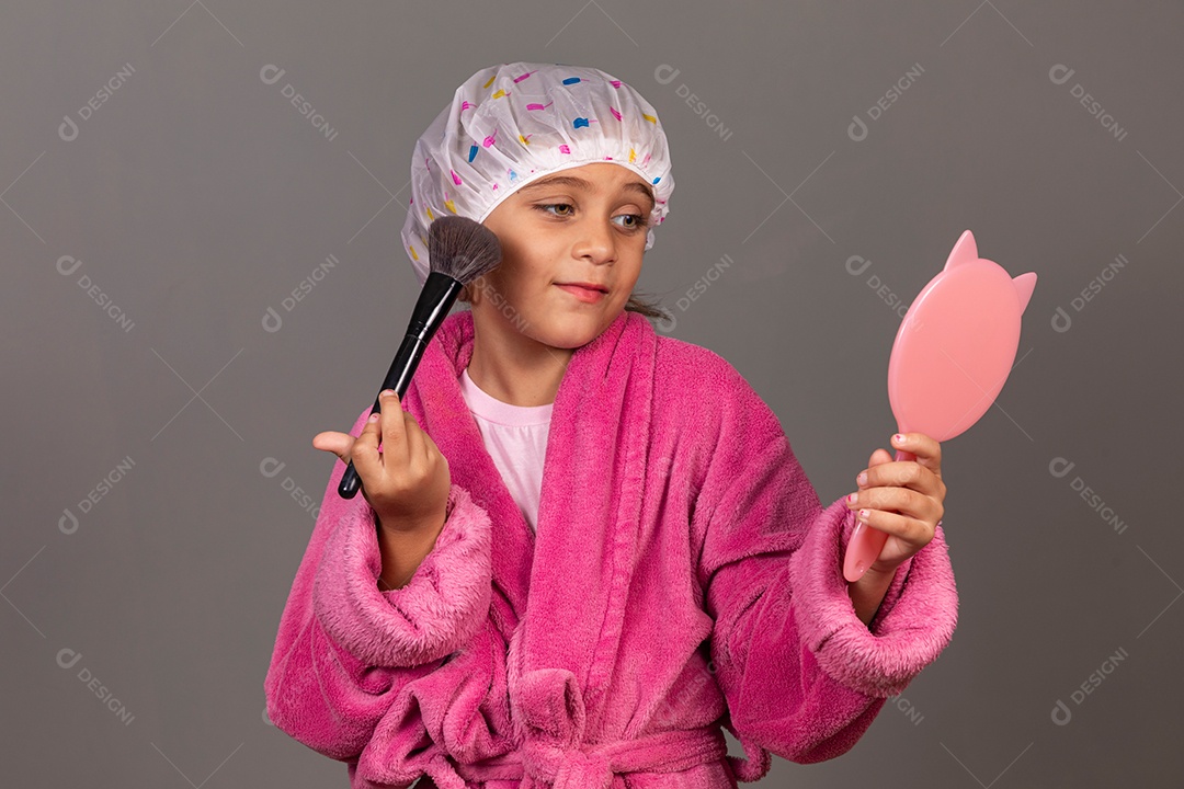 Linda menina usando roupão de banho rosa touca pincel e espelho sobre fundo isolado