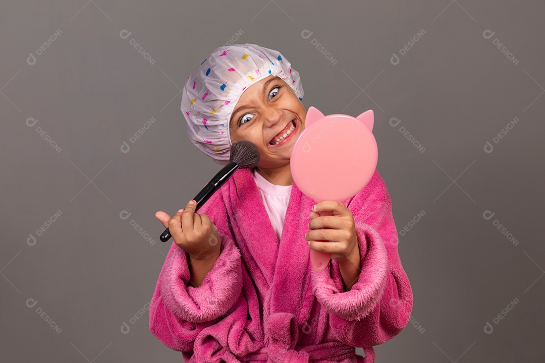 Linda menina usando roupão de banho rosa touca pincel e espelho sobre fundo isolado