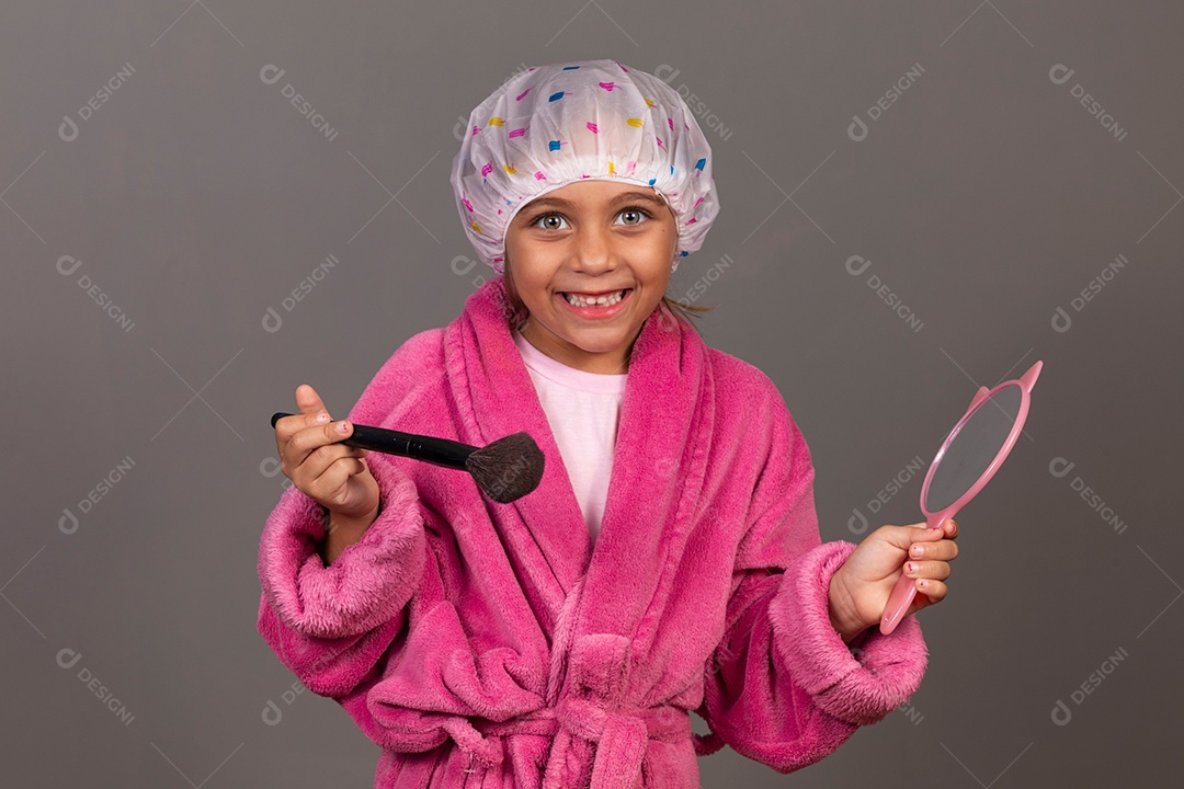 Linda menina usando roupão de banho rosa touca pincel e espelho sobre fundo isolado