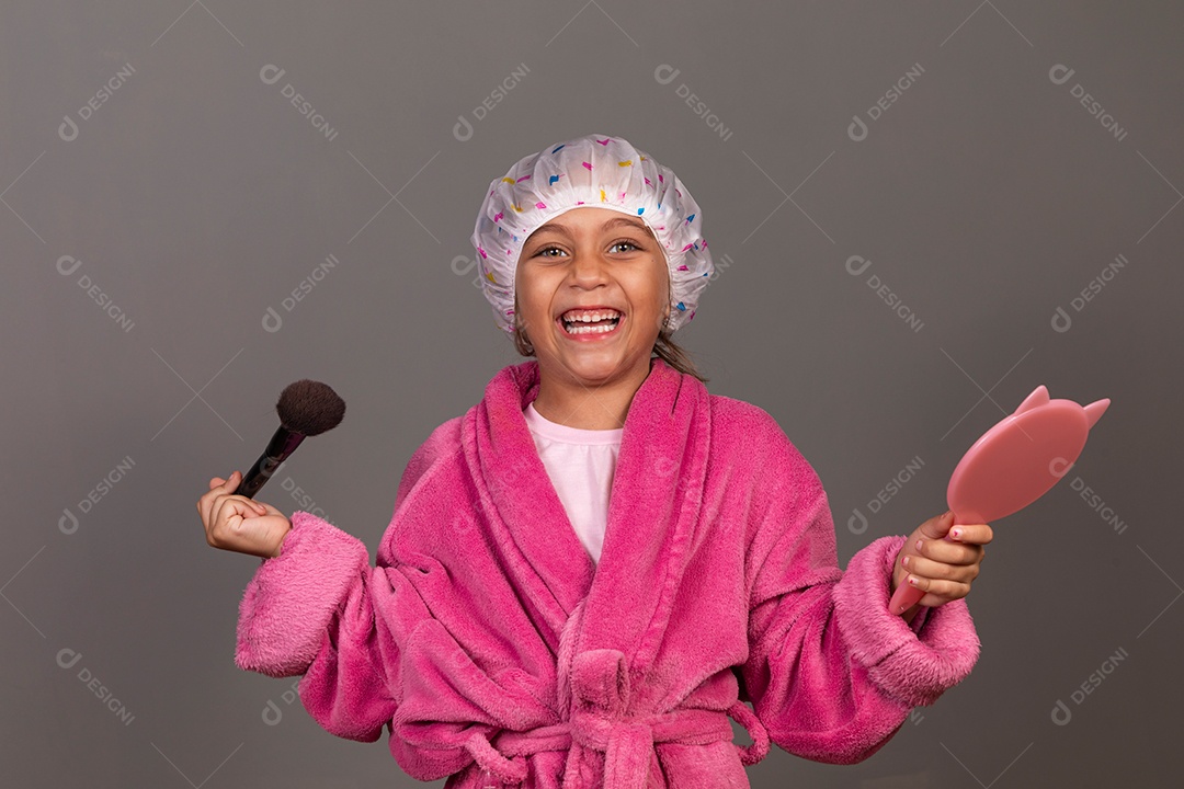 Linda menina usando roupão de banho rosa touca pincel e espelho sobre fundo isolado