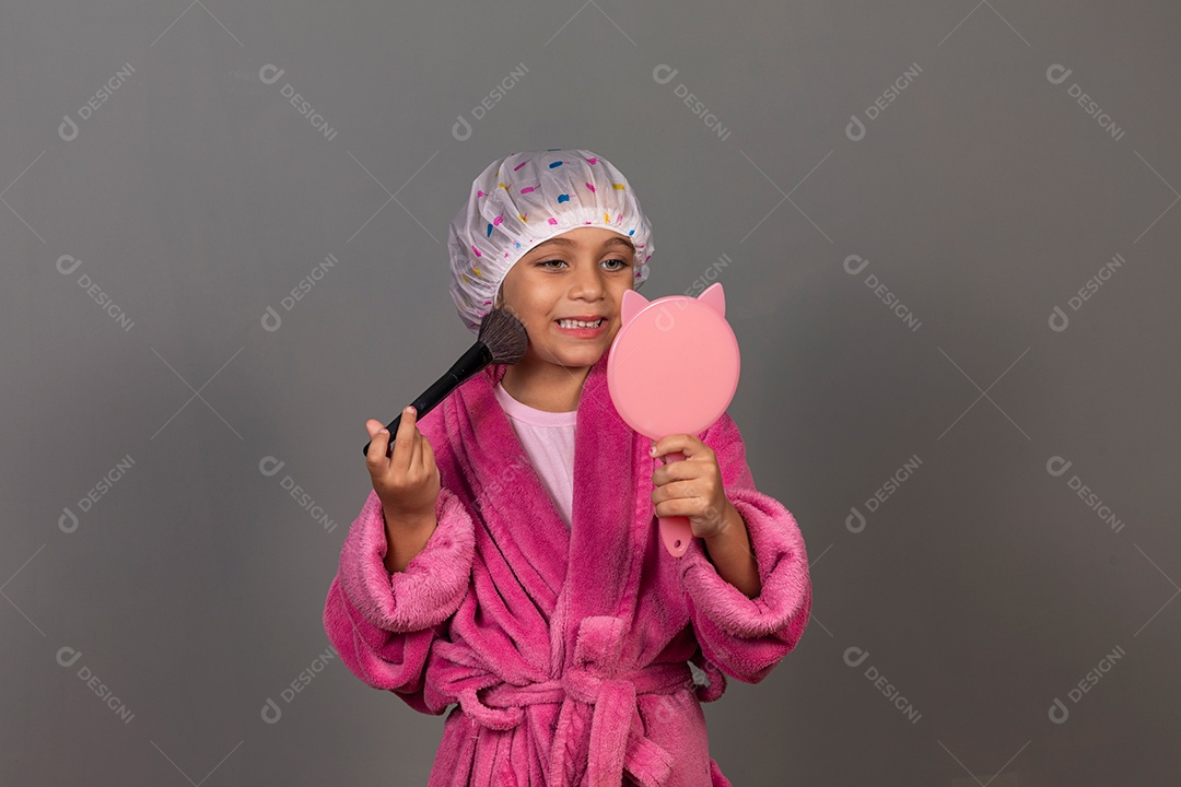 Linda menina usando roupão de banho rosa touca pincel e espelho sobre fundo isolado