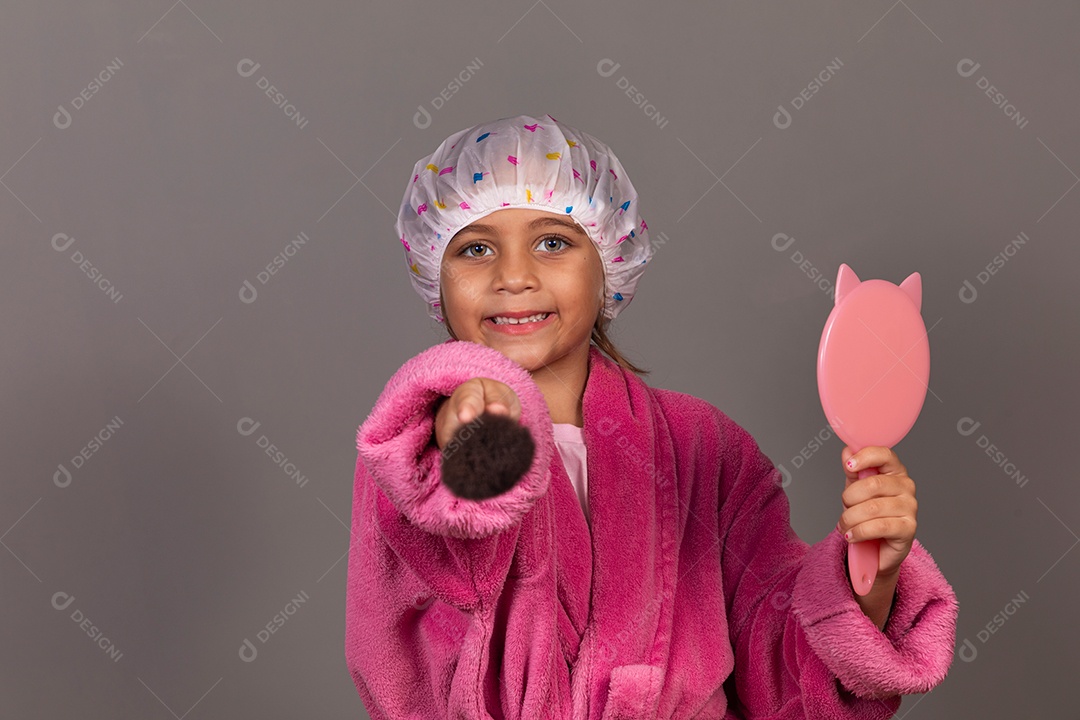 Linda menina usando roupão de banho rosa touca pincel e espelho sobre fundo isolado