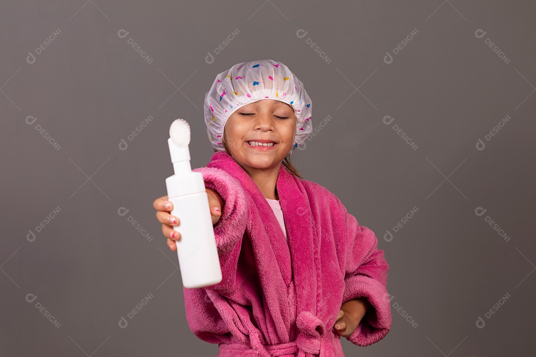 Linda menina usando roupão de banho rosa touca esfoliante sobre fundo isolado