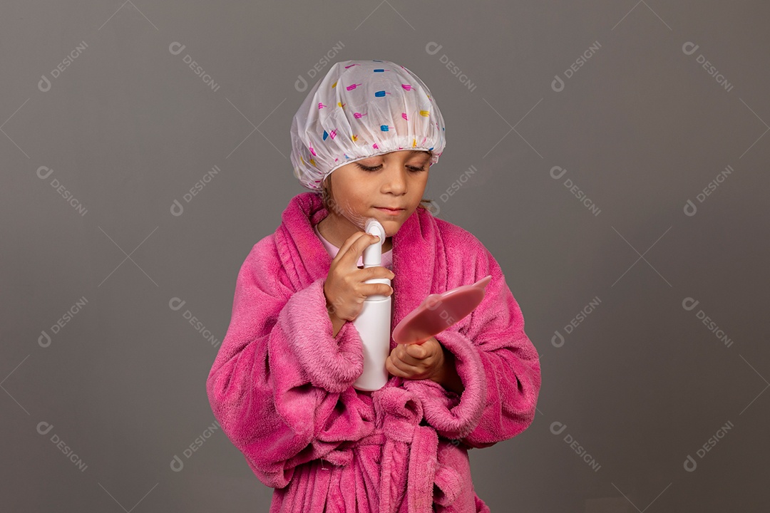 Linda menina usando roupão de banho rosa touca esfoliante espelho sobre fundo isolado