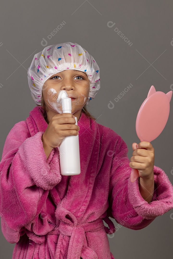 Linda menina usando roupão de banho rosa touca esfoliante espelho sobre fundo isolado