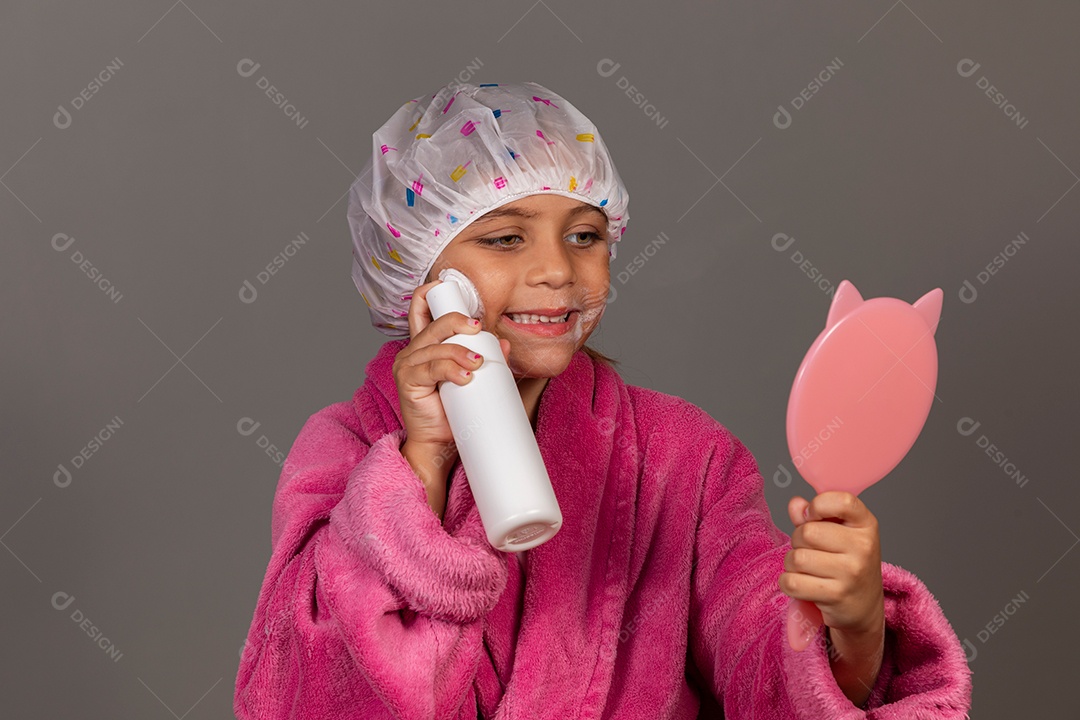 Linda menina usando roupão de banho rosa touca esfoliante e espelho sobre fundo isolado