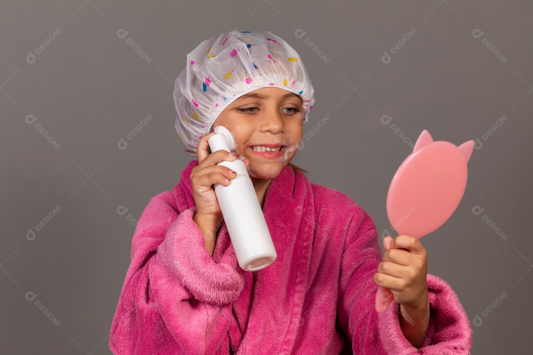 Linda menina usando roupão de banho rosa touca esfoliante espelho sobre fundo isolado