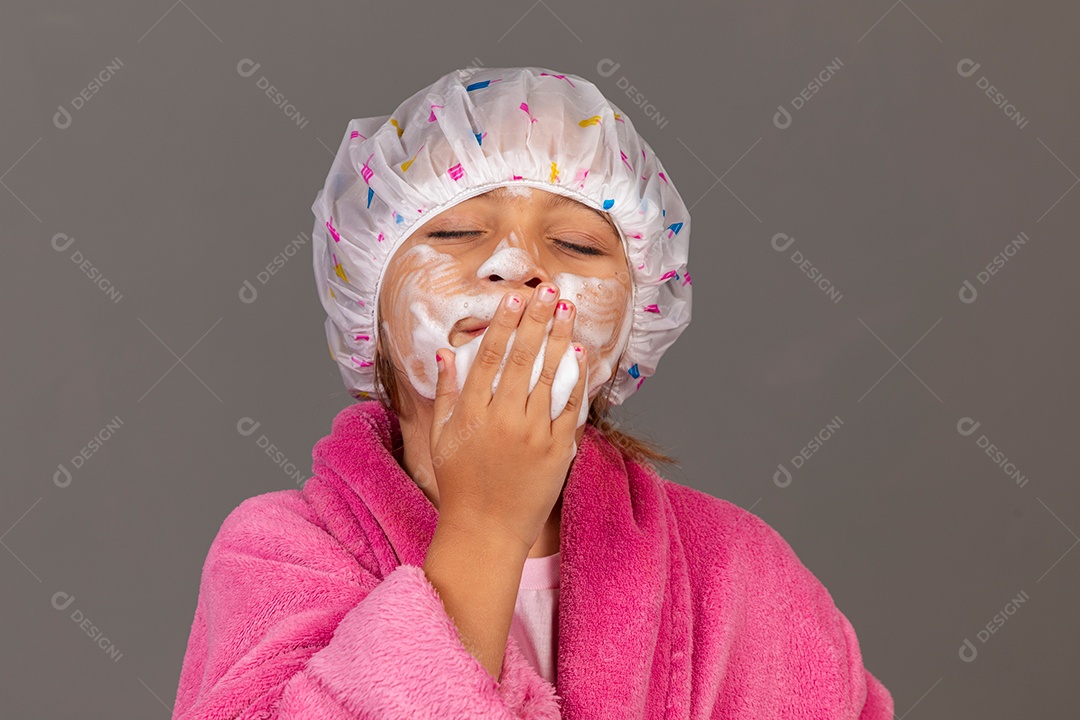 Linda menina usando roupão de banho rosa touca esfoliante sobre fundo isolado
