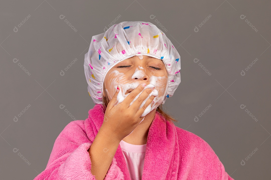 Linda menina usando roupão de banho rosa touca esfoliante sobre fundo isolado