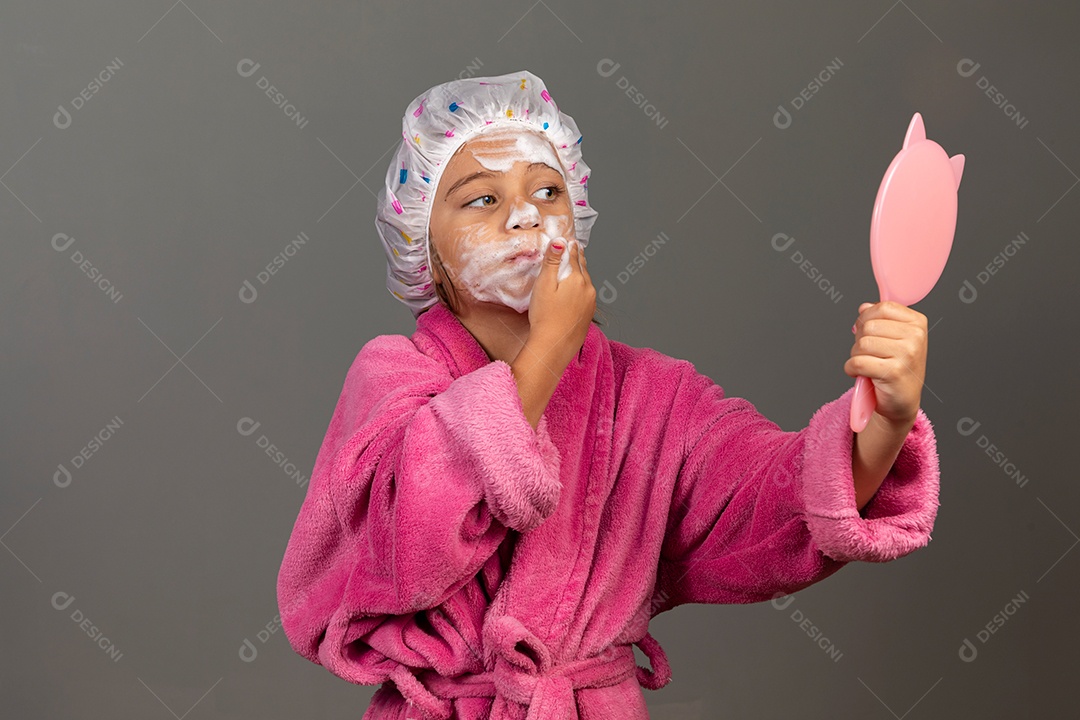 Linda menina usando roupão de banho rosa touca esfoliante espelho sobre fundo isolado