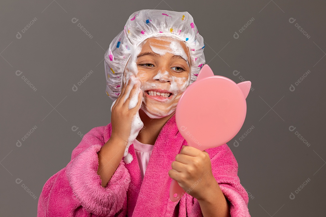 Linda menina usando roupão de banho rosa touca esfoliante e espelho sobre fundo isolado