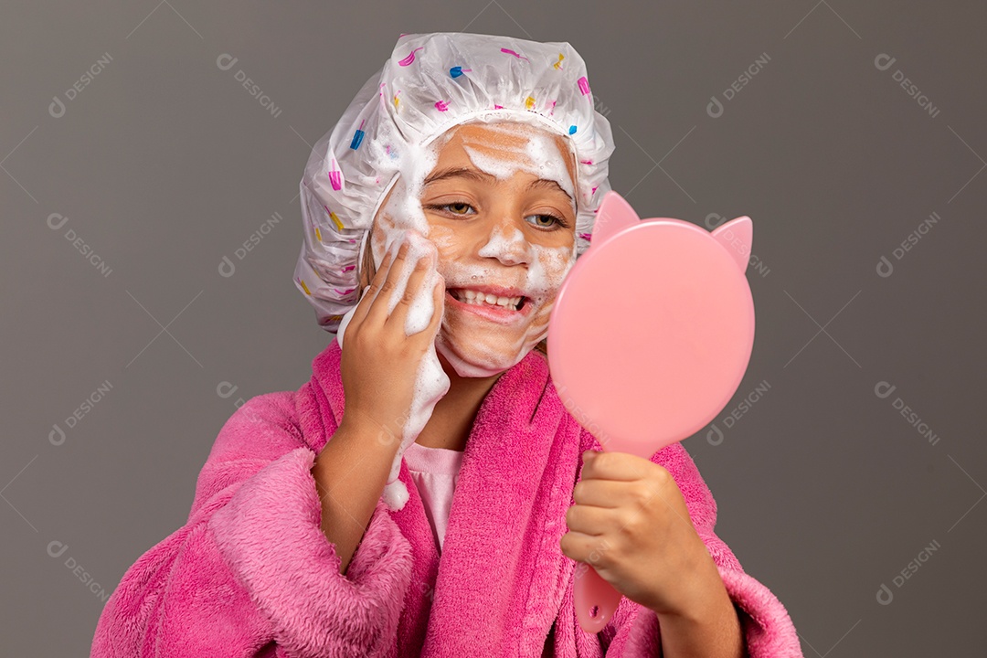Linda menina usando roupão de banho rosa touca esfoliante e espelho sobre fundo isolado