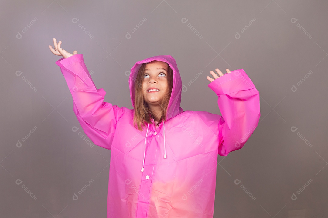 Garota linda usando capa de chuva rosa sobre fundo isolado