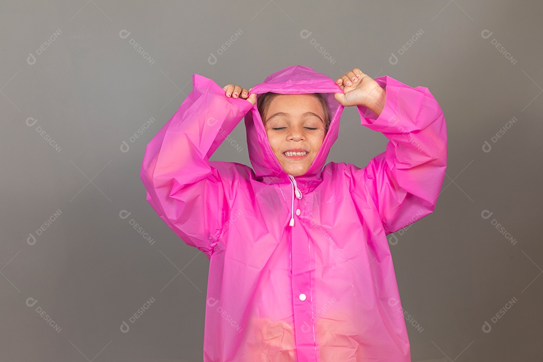 Garota linda usando capa de chuva rosa sobre fundo isolado