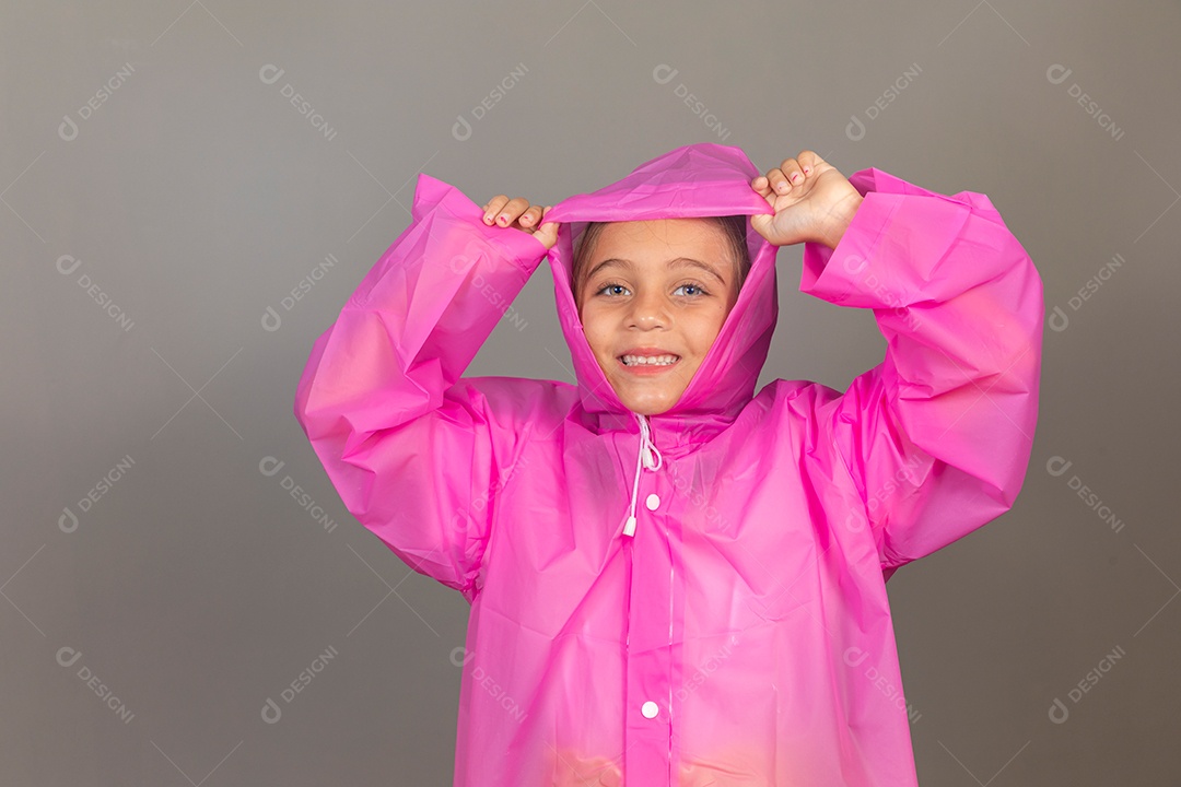 Garota linda usando capa de chuva rosa sobre fundo isolado