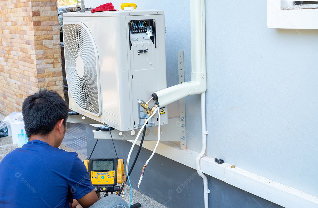 Técnico masculino instalando unidade externa de ar condicionado para resfriar a casa no verão