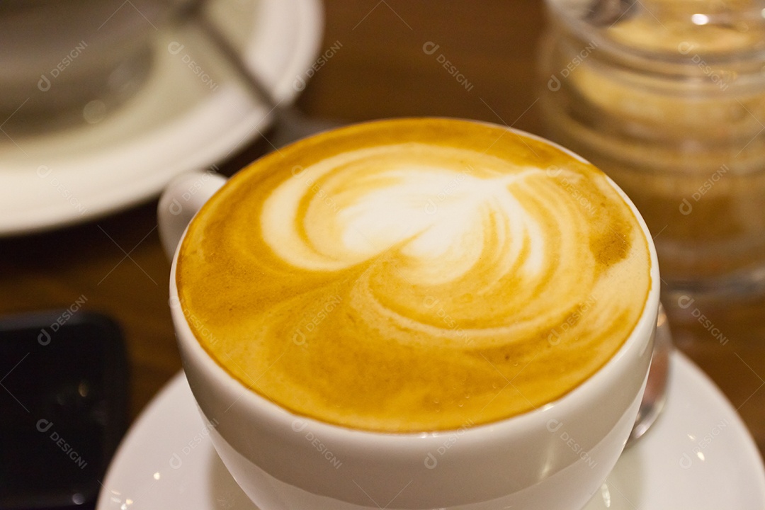 Cappuccino em xícara em prato sobre mesa de madeira