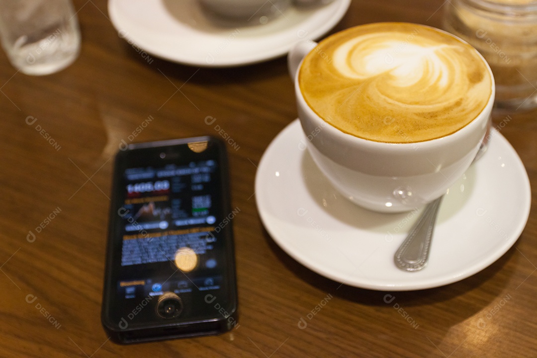 Cappuccino em xícara em prato ao lado de smartphone tecnologia avançada sobre mesa de madeira