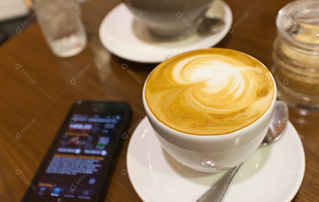 Cappuccino em xícara em prato ao lado de smartphone tecnologia avançada sobre mesa de madeira
