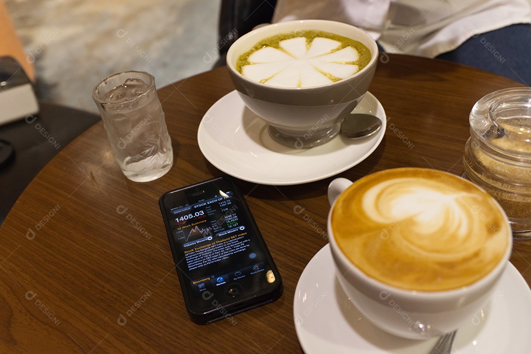 Cappuccino em xícara em prato ao lado de smartphone tecnologia avançada sobre mesa de madeira