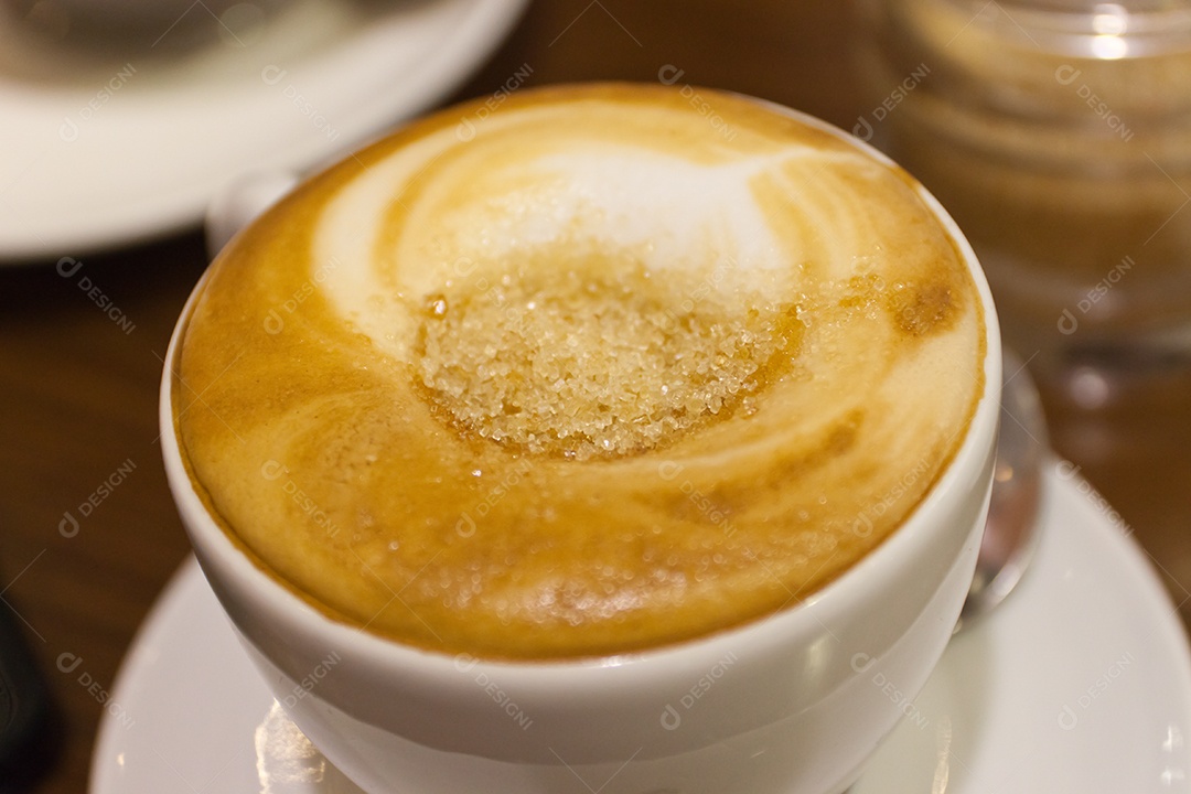 Cappuccino em xícara em prato sobre mesa de madeira