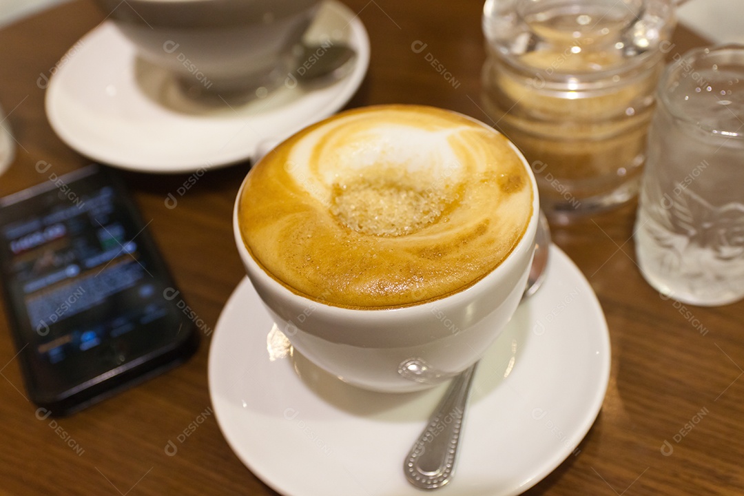 Cappuccino em xícara em prato ao lado de smartphone tecnologia avançada sobre mesa de madeira