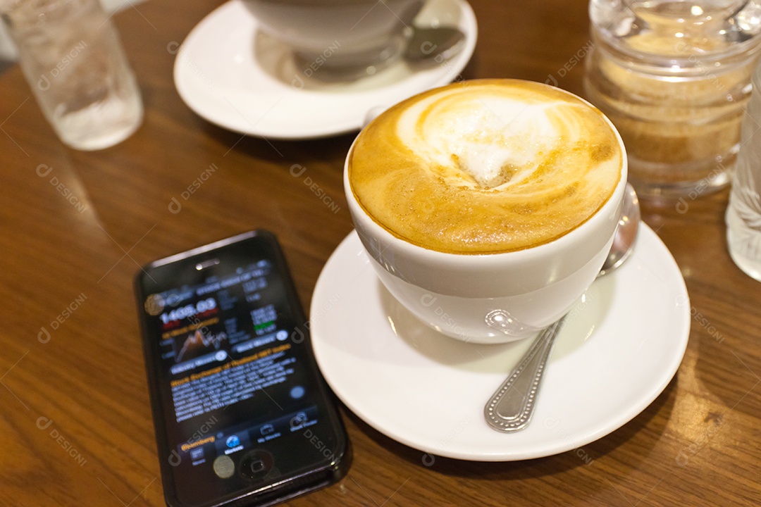 Cappuccino em xícara em prato ao lado de smartphone tecnologia avançada sobre mesa de madeira