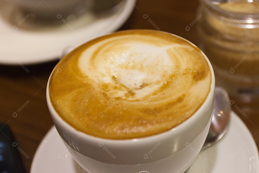 Cappuccino em xícara em prato sobre mesa de madeira