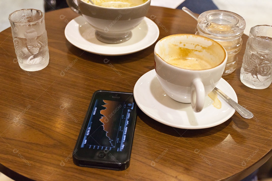 Smartphone ao lado de xícara de café sobre uma mesa de madeira