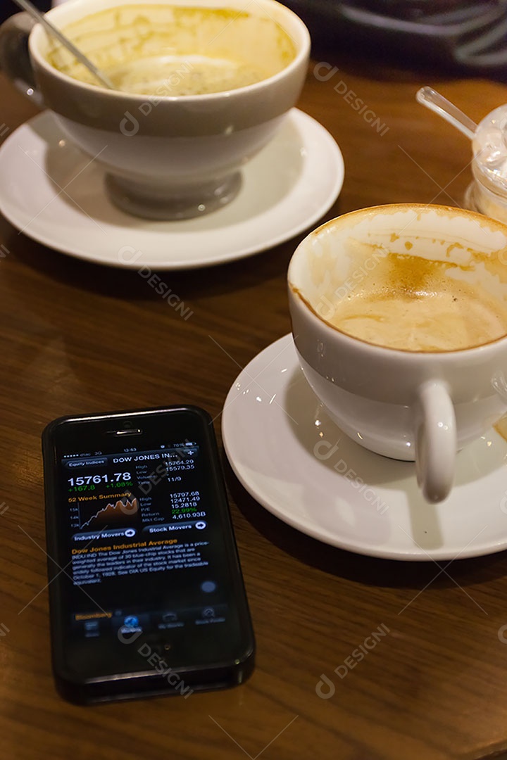 Smartphone ao lado de xícara de café sobre uma mesa de madeira