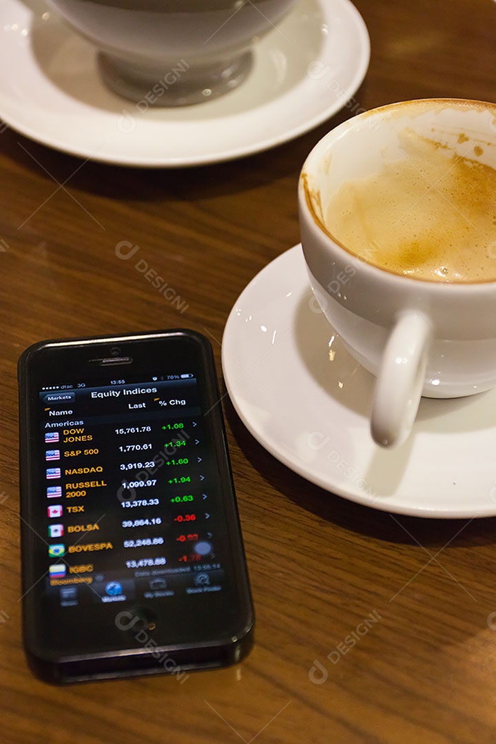 Smartphone ao lado de xícara de café sobre uma mesa de madeira