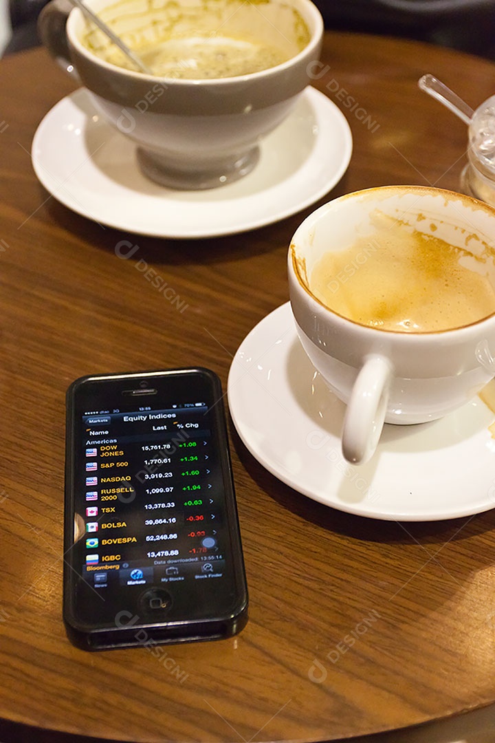 Smartphone ao lado de xícara de café sobre uma mesa de madeira