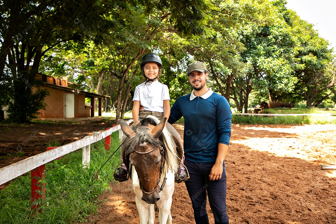 Filha montada a cavalo ao lado do seu pai sobre uma fazenda