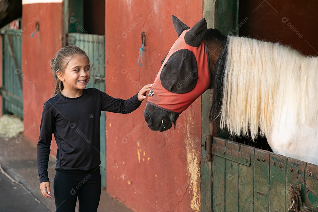 Garota linda acarissiando cavalo sobre uma fazenda