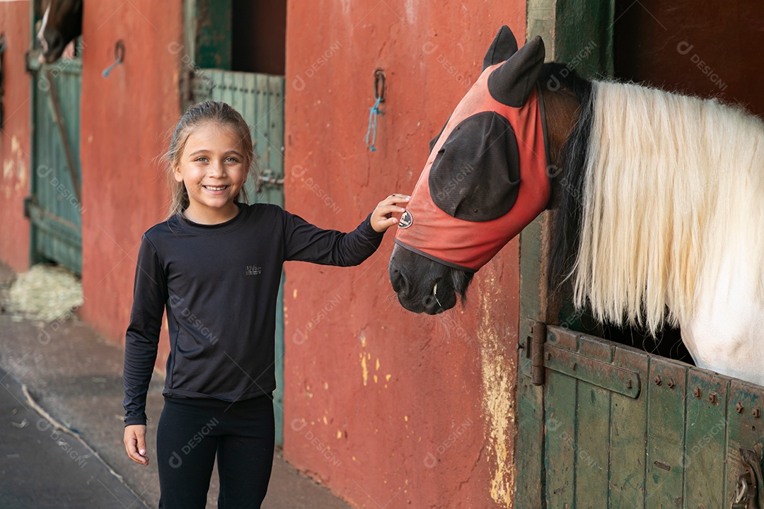 Garota linda acarissiando cavalo sobre uma fazenda