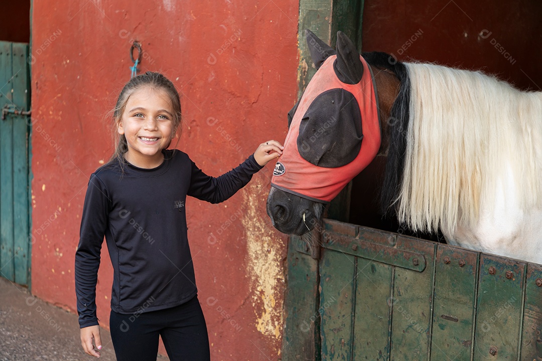 Garota linda acarissiando cavalo sobre uma fazenda