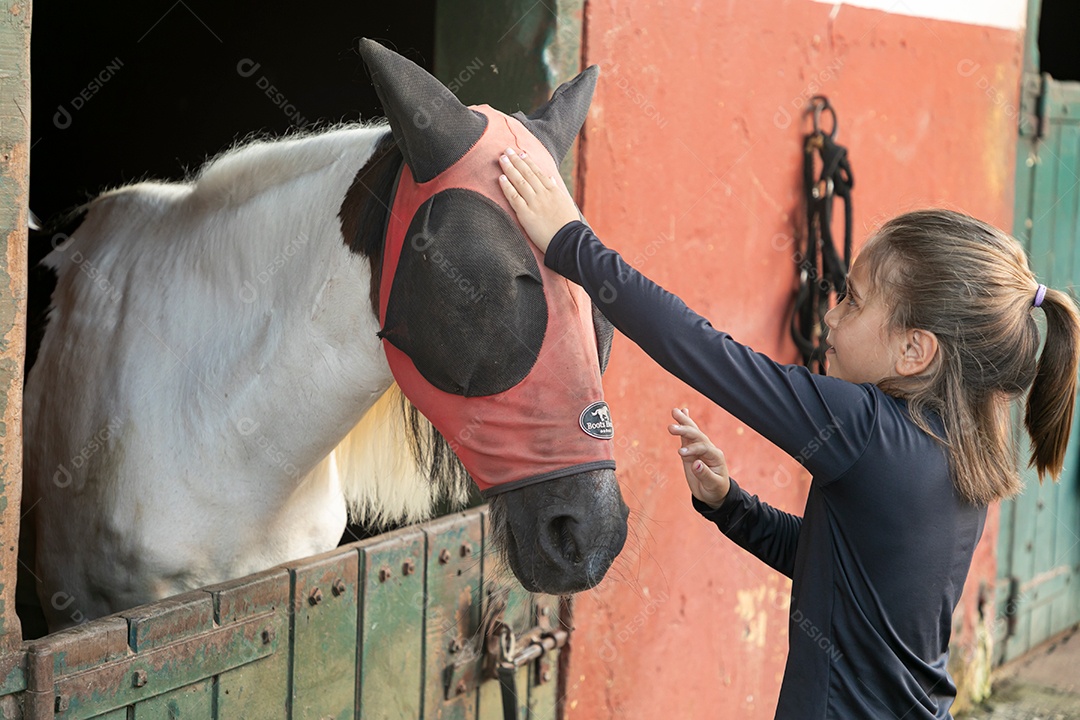 Garota linda acarissiando cavalo sobre uma fazenda