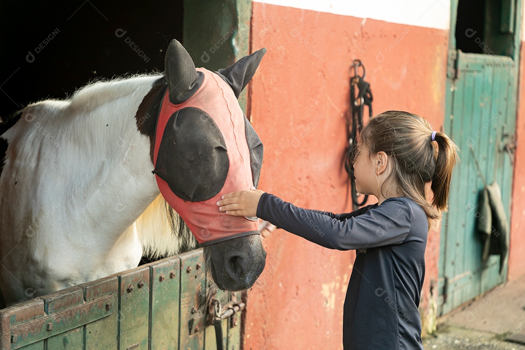 Garota linda acarissiando cavalo sobre uma fazenda