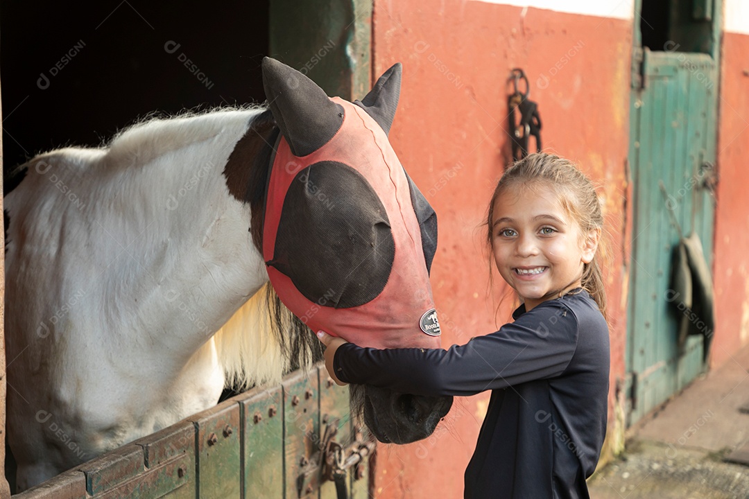 Garota linda acarissiando cavalo sobre uma fazenda