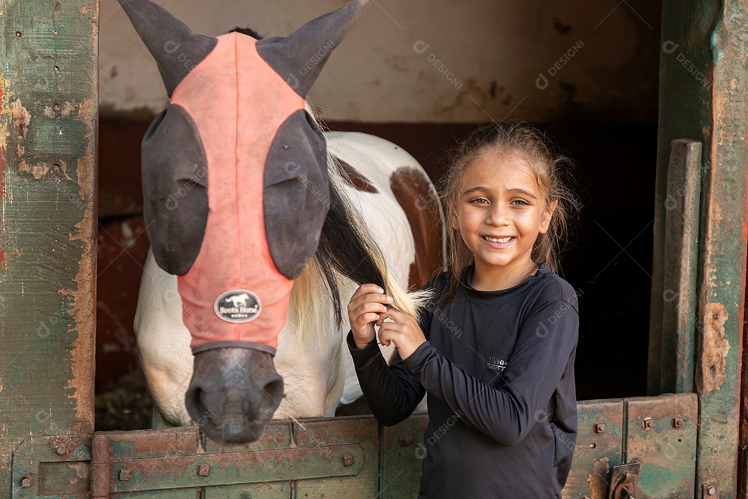 Garota linda acarissiando cavalo sobre uma fazenda