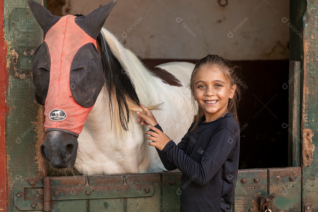 Garota linda acarissiando cavalo sobre uma fazenda