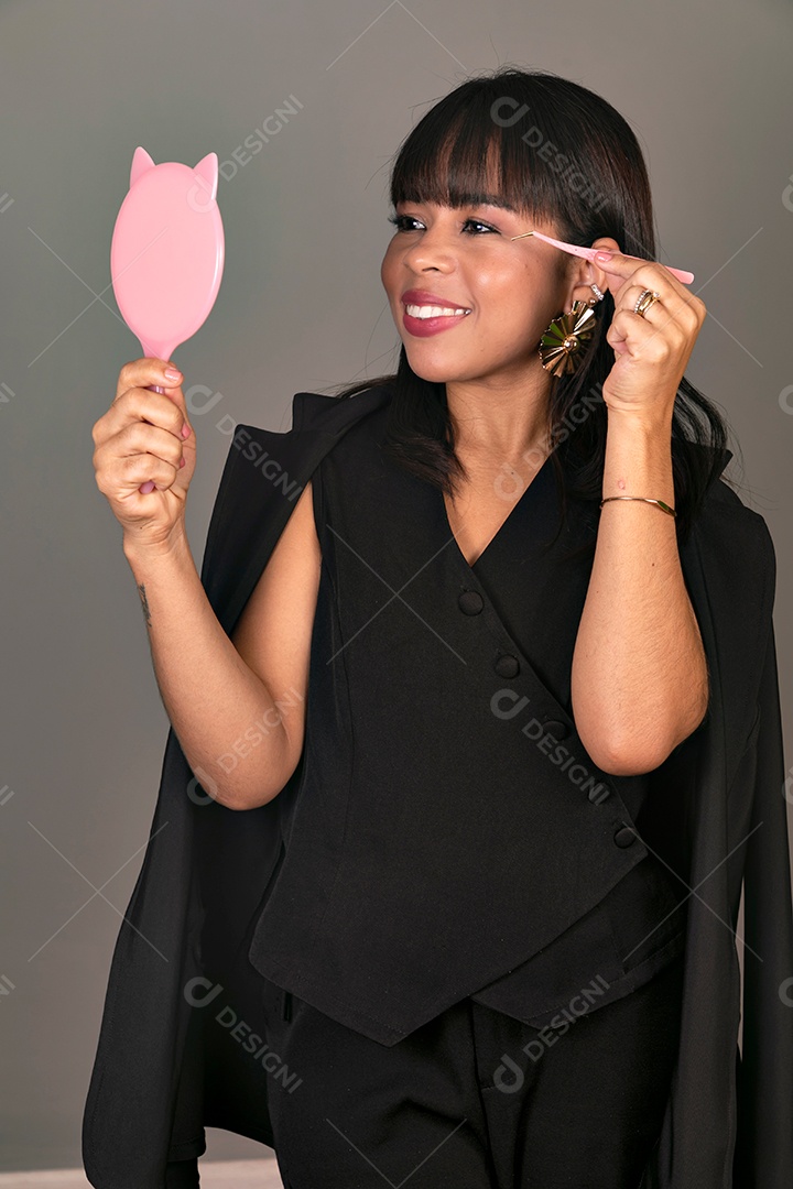 Linda mulher segurando espelho e pinça sobre fundo isolado