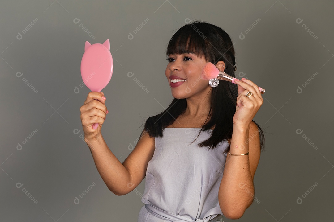 Linda mulher segurando espelho e pincel sobre fundo isolado