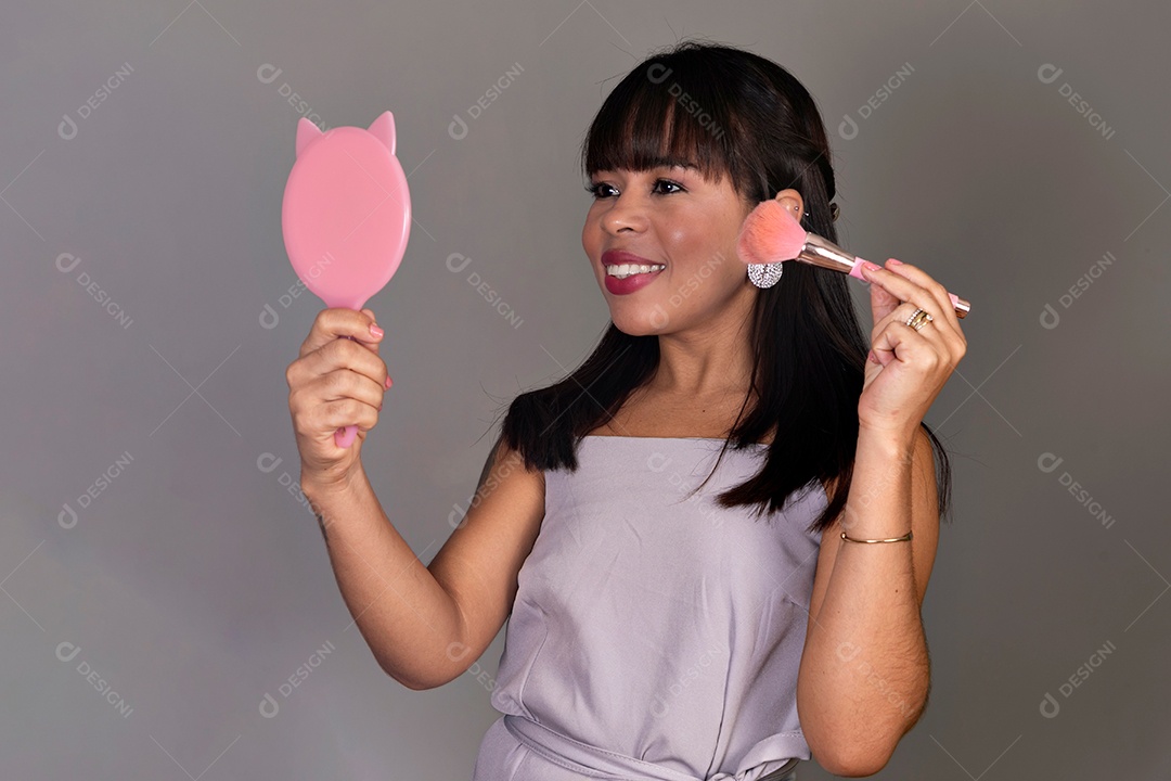 Linda mulher segurando espelho e pincel sobre fundo isolado